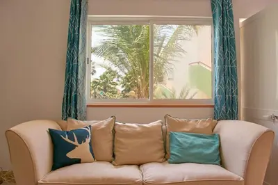 a couch with pillows sitting in a room with a window at Apartamento T3 encantador com piscina wifi e perto de praia in Santa Maria
