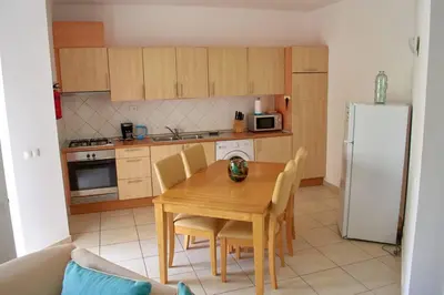 a kitchen with a wooden table with chairs and a refrigerator at Apartamento T3 encantador com piscina wifi e perto de praia in Santa Maria