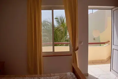 a bedroom with a window with a view of a palm tree at Apartamento T3 encantador com piscina wifi e perto de praia in Santa Maria