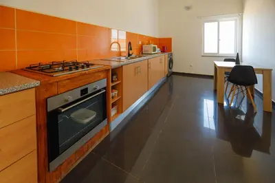 a kitchen with wooden cabinets and a stove top oven at Chambre 3 Residencial Eunice in Praia