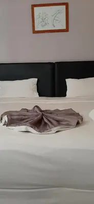 a bed with white sheets and a brown blanket at Atlantic Maio Hotel in Vila do Maio