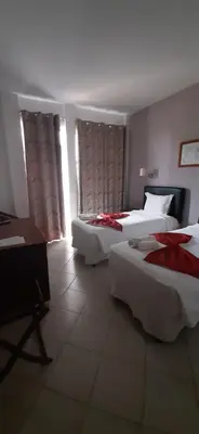 a hotel room with two beds and a desk at Atlantic Maio Hotel in Vila do Maio