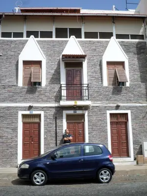 a blue car parked in front of a brick building at Casa Privada do Plateau in Praia