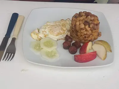 a plate of food with eggs beans and fruit at Residencial Rosa Criola in Sal Rei
