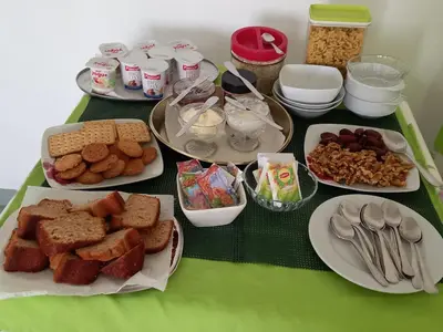 a green table topped with plates of food and desserts at Residencial Rosa Criola in Sal Rei