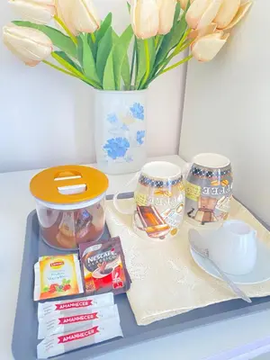 a tray with two cups and a vase with flowers at Quarto Nº5 FANTASTIQUE- Central Praia in Praia