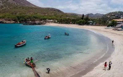 people standing on a beach with boats in the water at Praia Center in Praia