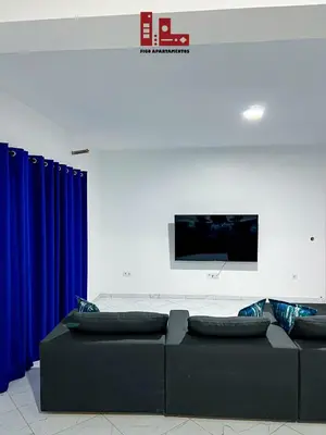 a living room with blue curtains and a couch at Figo Apartamentos in Praia