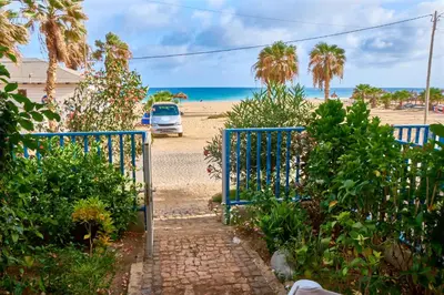 a blue gate leading to a beach with a car at Leme Bedje Sea View - By Bobbywashere in Santa Maria