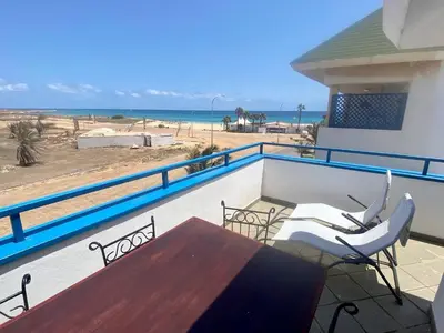 a balcony with a table and chairs and the beach at Leme Bedje Sea View - By Bobbywashere in Santa Maria