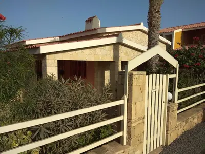 a white fence next to a house with a gate at Casita Solemar direkt am Atlantik in Vila do Maio