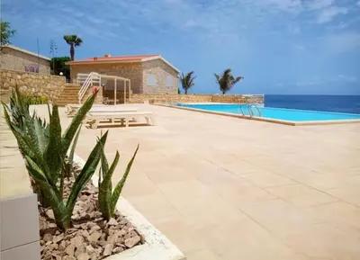a resort with a swimming pool and the ocean at Casita Solemar direkt am Atlantik in Vila do Maio