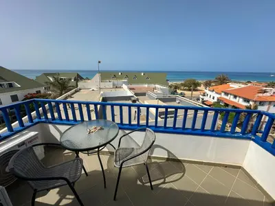 a balcony with two chairs and a table and the ocean at Leme Bedje Three bedroom - By Bobbywashere in Santa Maria
