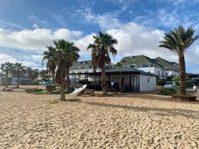 a beach with palm trees in front of a building at Leme Bedje Three bedroom - By Bobbywashere in Santa Maria
