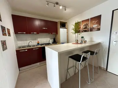 a kitchen with brown cabinets and a counter with stools at Leme Bedje Two bedroom - By Bobbywashere in Santa Maria