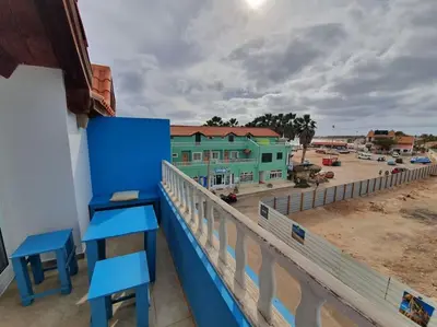 a balcony with blue chairs and a view of a building at Holiday Properties Soleil Penthouse in Santa Maria