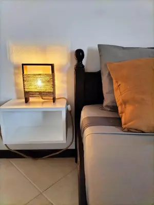 a bedside table with a lamp next to a bed at Solstice in Santa Maria