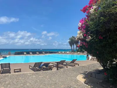 a swimming pool with chairs and the ocean in the background at Porto Antigo 1 - Three bedroom, pool & wifi in Santa Maria