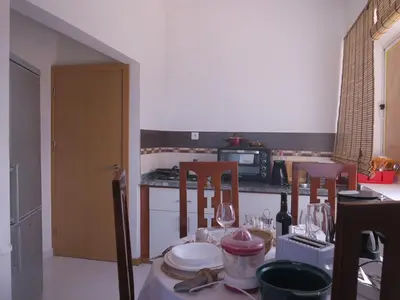 a kitchen with a table with two chairs and a table with wine glasses at Casa de Nômades Digitais in Mindelo