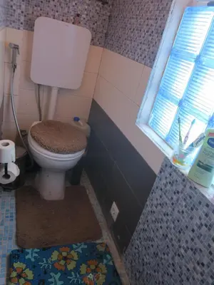 a bathroom with a toilet and a window and a rug at Casa de Nômades Digitais in Mindelo