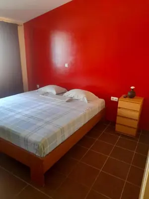 a bedroom with a bed with a red wall at SAM House in Mindelo
