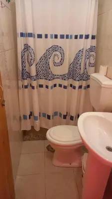 a bathroom with a toilet and a shower curtain at SAM House in Mindelo