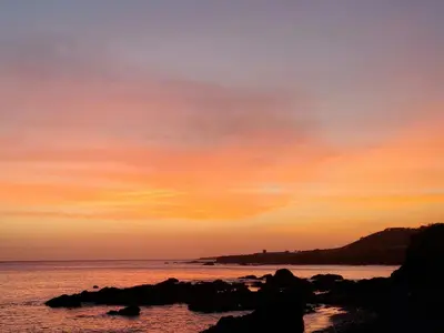 a sunset over the ocean with rocks in the water at Villa Halcyon cabo verde close to the beach in Cidade Velha