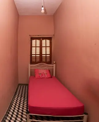 a small bedroom with a red bed with a window at Casa Matnik in Mindelo