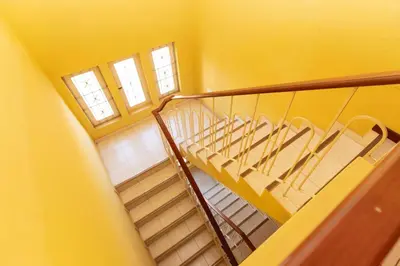a spiral staircase in a yellow room with two windows at Studio Maya Mindelo in Mindelo