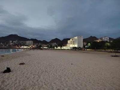 a black cat sitting on a sandy beach at Studio Maya Mindelo in Mindelo