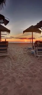 a group of chairs and umbrellas on a beach at Oasis Palmeira in Santa Maria