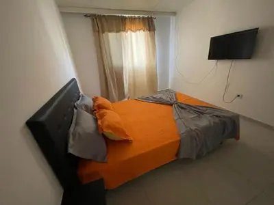 a bedroom with a bed with an orange blanket at Apartamento in Praia