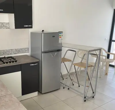 a kitchen with a refrigerator and a table and chairs at Apartamento in Praia