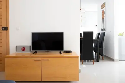 a television sitting on top of a wooden dresser at 2 bdr cozy apt near Praça Center, AC & Fast Wi-Fi in Praia