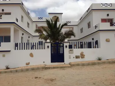 a house with a palm tree in front of it at Maio Relax in Vila do Maio