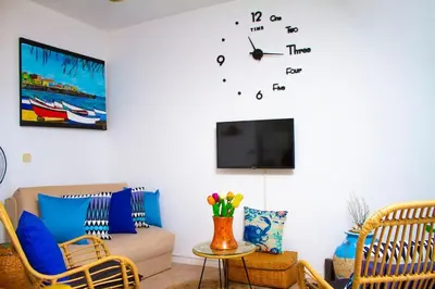 a living room with a couch and a clock on the wall at Relaxing Blue Flat near beach! in Calheta Do Maio
