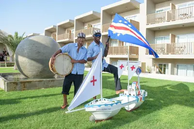 two men are standing on a small toy sail boat at Oasis Salinas Sea in Santa Maria