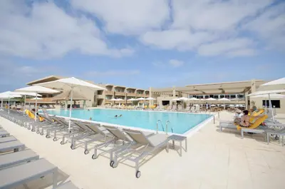 a large swimming pool with chairs and umbrellas at Oasis Salinas Sea in Santa Maria