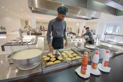 a man standing in a kitchen preparing food at Oasis Belorizonte in Santa Maria