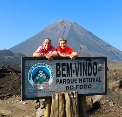 a man and woman standing behind a sign in front of a mountain at Rose silva in Portela