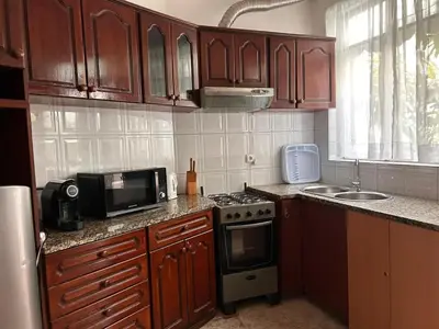 a kitchen with wooden cabinets and a stove and a microwave at Tarrafal Ecodécor Rooms in Tarrafal