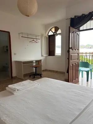 a bedroom with a white bed and a desk at Tarrafal Ecodécor Rooms in Tarrafal