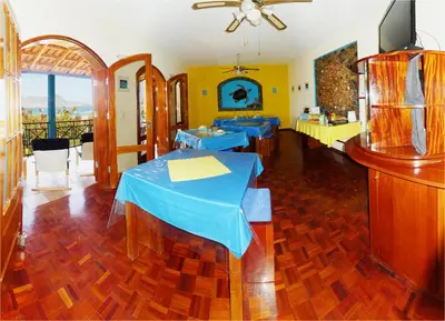 a dining room with two tables and a television at Solar Windelo in Mindelo