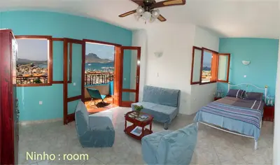 a bedroom with a bed and a chair and windows at Solar Windelo in Mindelo