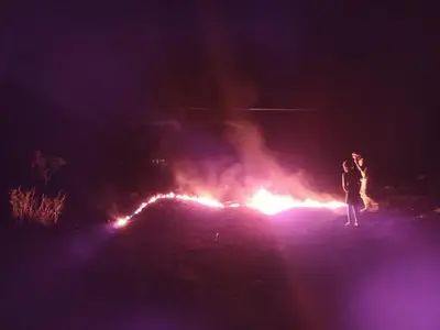 two people standing in front of a fire at night at Pensao Zé Doce in Portela