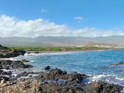 a beach with rocks and the ocean and mountains at Vila Babosa in Porto Novo