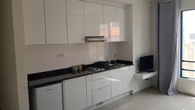 a white kitchen with white cabinets and a television at Apartamentos Beira-Mar in Mindelo