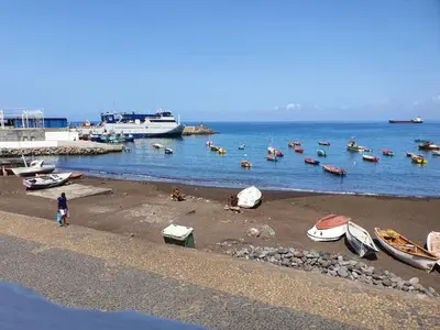 a beach with boats and a group of people in the water at Seaview Apartment in Tarrafal