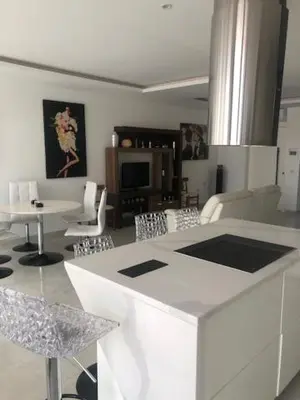 a kitchen and living room with a white counter and chairs at Apartamento Deluxe Santa Filomena in Mindelo