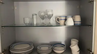 a shelf with glasses and plates and wine glasses at Apartamento T2 equipado Vila Verde in Santa Maria